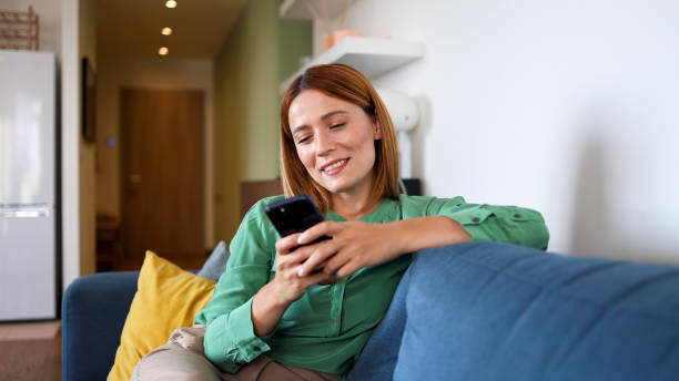 istock Woman relaxing on the couch and using smartphone 2164897950