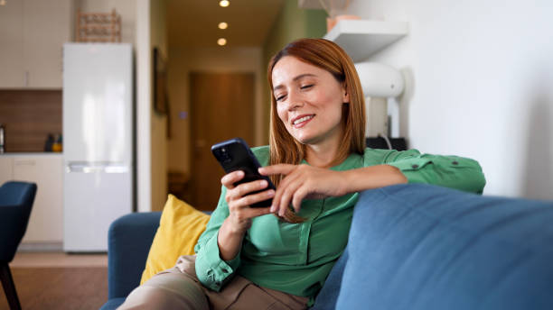 istock Woman relaxing on the couch and using smartphone 2164897952