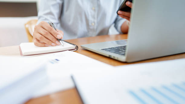 istock Close up woman working on laptop and using mobile phone in office. 2164904034