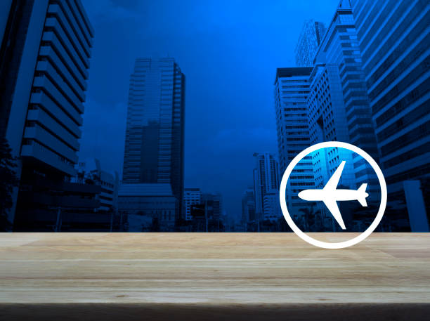 Airplane icon on wooden table over modern office city tower, Business transportation service concept