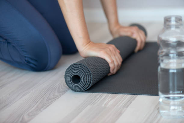 istock Woman Rolling Yoga Mat 2164910401