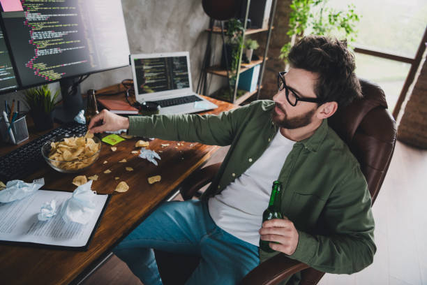 istock Photo of professional it specialist young man beer chips computer desktop loft interior office indoors 2164914795