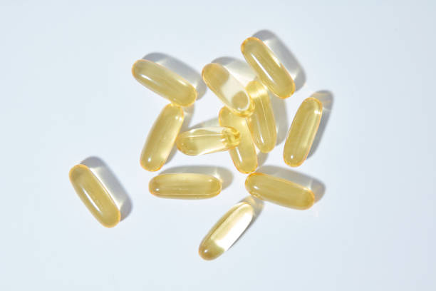 The unique template photograph was shot from top view for advertisement with a pile of yellow fish oil capsules standing out on white background. Blank space for designing and advertising