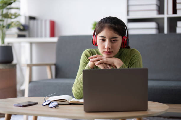 istock Young Woman Feeling Stressed While Working Online from Home, Wearing Headphones and Using Laptop in Modern Living Room 2164927258