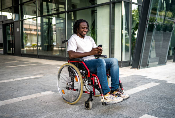 istock Cheerful man in a wheelchair using a smartphone outdoors 2164932952