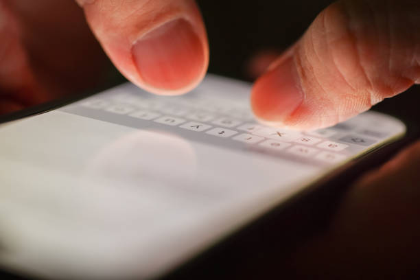 Close-up of fingers typing on mobile phone screen keyboard; Shallow depth of field.