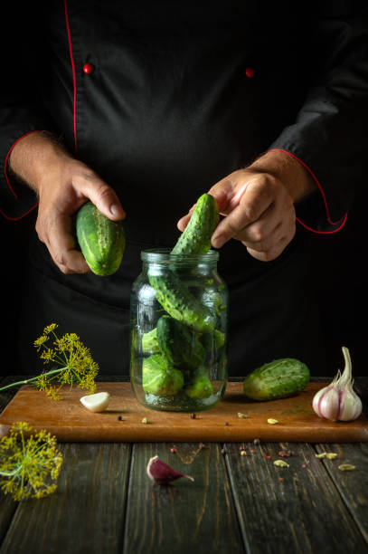 istock A man manually fills a jar with cucumbers before preserving them with spices on the kitchen table. Concept of pickling delicious cucumbers at home 2164934447