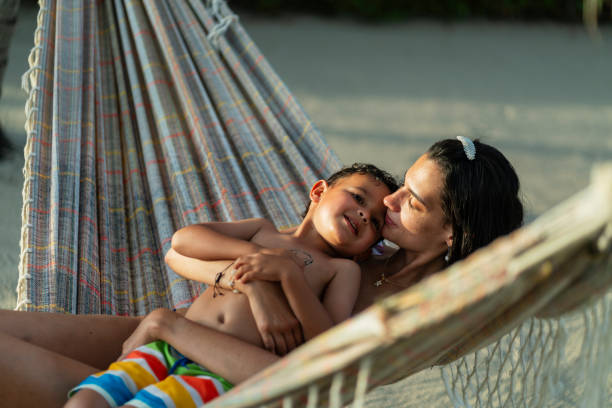 istock Latin woman using the hammock where she rests while enjoying the sunset wearing her swimsuit and playing with her 4-year-old son on a magical sunny afternoon 2164935084