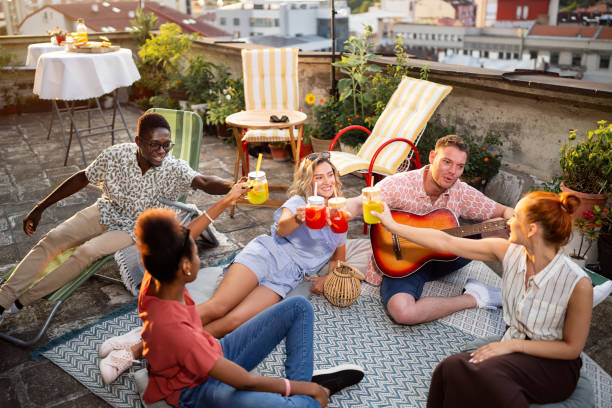 istock Multiracial friends toasting with mocktails, while hangout on a rooftop and playing acoustic guitar 2164941981