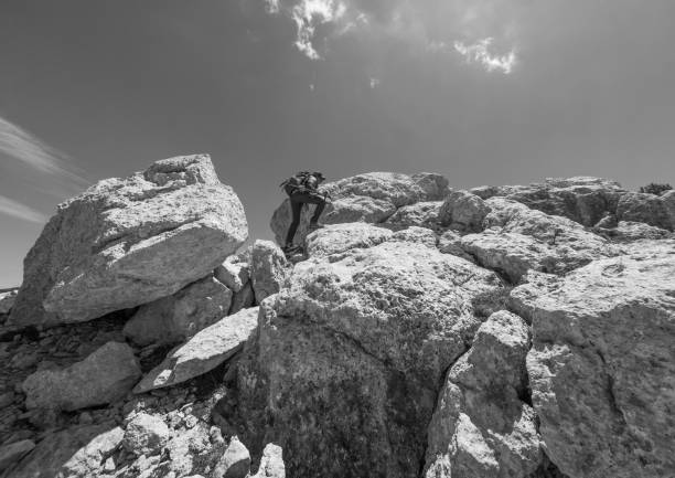 National park of Majella, Italy - 17 June 2024 - Mountain summits in the Majella range, central Italy, Abruzzo region, with characteristic landscape of rocky expanses between valleys and plateaus. Here in particular a view of Pescofalcone Mount with girl hiker in the rock path