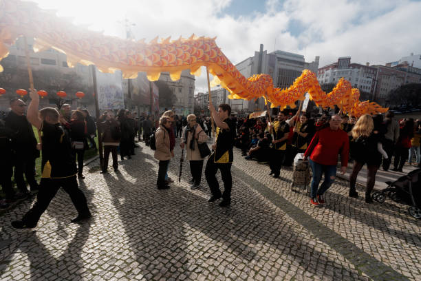 Lisbon, Portugal - January 18, 2020: Men carrying a giant dragon and dressed in traditonal folklore costumes, parade in Lisbon downtown during the celebrations of the Chinese New Year.