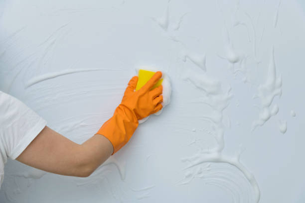 istock Woman hand cleaning blue wall with sponge 2164953385