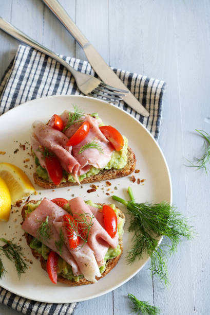 Avocado toast with prosciutto and tomato.