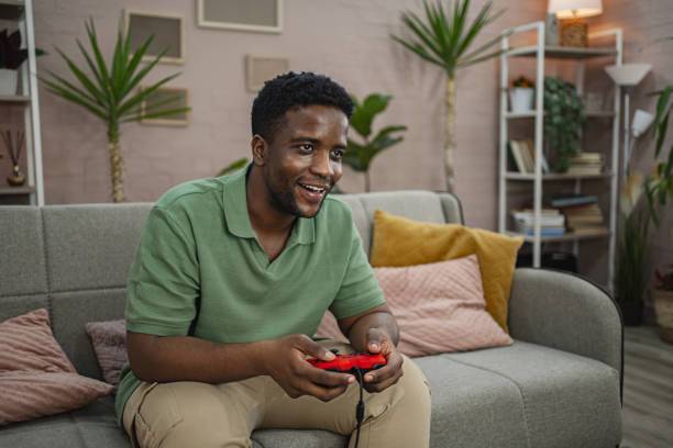 istock Young black man playing a video game at home 2164957922