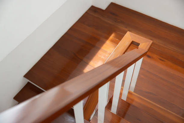 View up a staircase toward an arched window, the brass handrail banister in sharp focus the steps and window in soft focus with simple available light