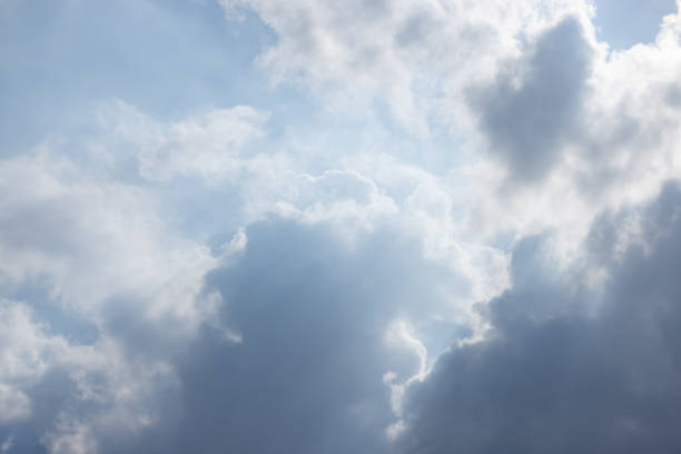 The sky is cloudy and the sun is shining through the clouds. The clouds are white and fluffy, and the sky is blue