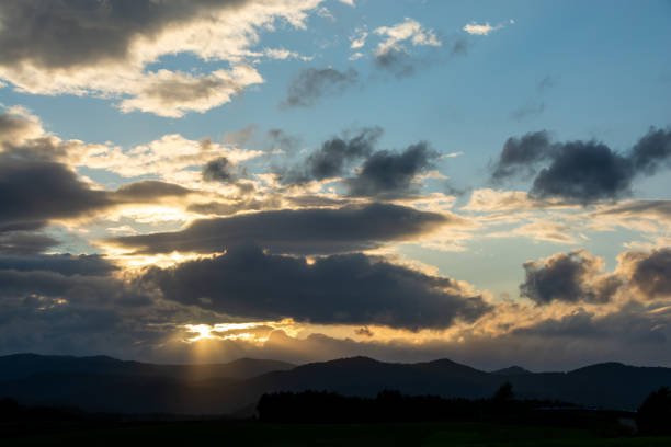 The sun sets over the mountain. The clouds cover it.