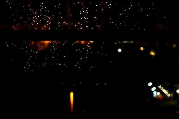 Mesmerizing urban bokeh through raindrops on window glass creating a cozy atmosphere. The glitter of bokeh city lights through the window.