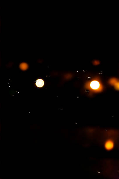 Mesmerizing urban bokeh through raindrops on window glass creating a cozy atmosphere. The glitter of bokeh city lights through the window.
