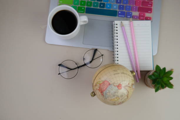 flatlay of a workplace with A cup of coffee, a laptop and a notebook, on a grey table. Education, business and office concept.