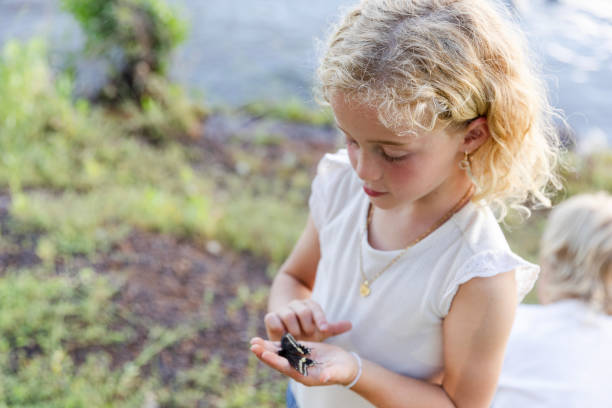 istock Elementary age girl studies butterfly while on field trip 2164968986