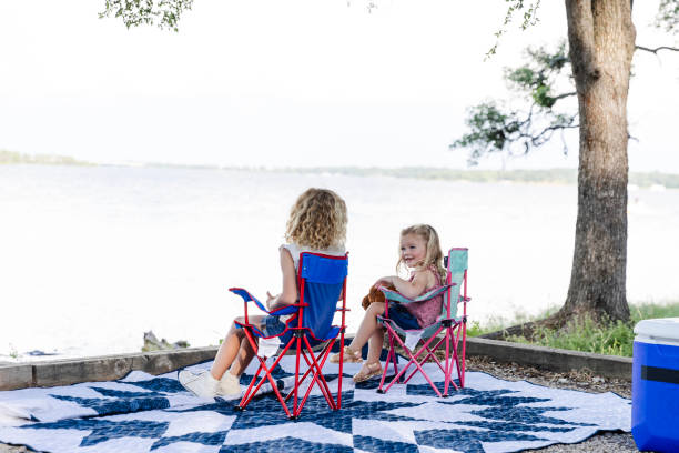 istock Young sisters sit by lake and chat 2164969079