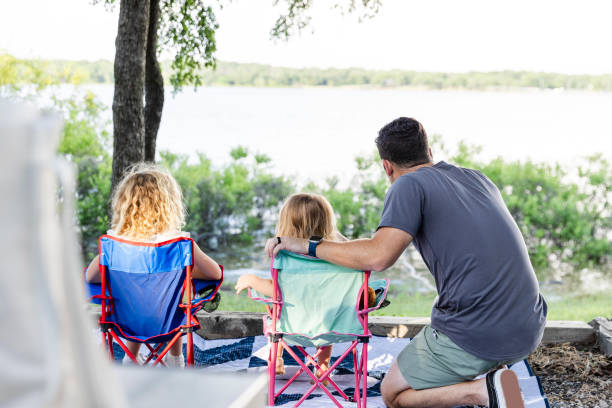 istock Unrecognizable dad and two daughters look out at lake 2164969103