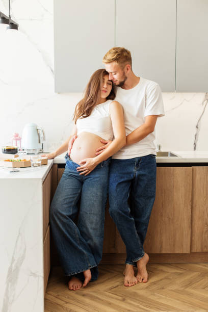 istock Pregnant Couple Embracing in Cozy Kitchen. 2164969139