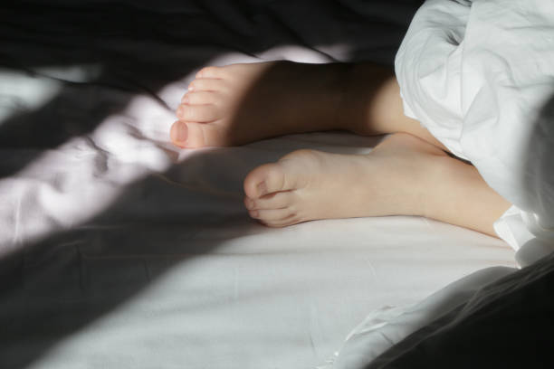 istock Child feet under the white blanket under soft morning light 2164975331