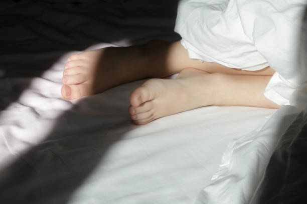 istock Child feet under the white blanket under soft morning light 2164975547