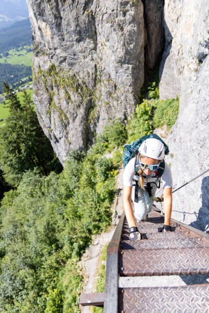 istock Adventurous climber ascending steep metal ladder on mountain trail 2164976717