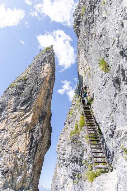 istock Climber scaling high metal ladder on mountain trail 2164976828