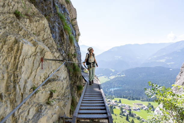 Climber scaling high metal ladder on mountain trail