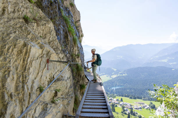 istock Climber scaling high metal ladder on mountain trail 2164976848