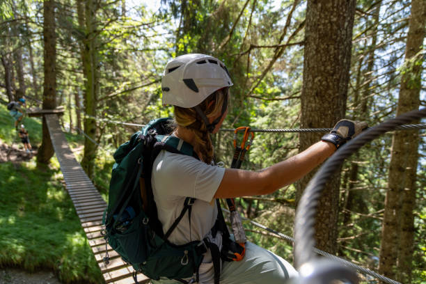 Female climber balancing on forest suspension bridge