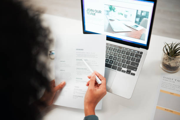 Hands, pen and human resources with CV, laptop with hiring news on company website and recruitment in office. Person reading resume, employee choice and onboarding, job application and information manos, bolígrafo y recursos humanos con cv, portátil con noticias de contratación en la web de la empresa y reclutamiento en oficina. lectura del currículum vitae, elección e incorporación de empleados, solicitud de empleo y vista trasera