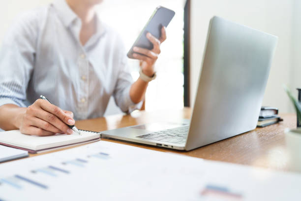 istock Close up woman working on laptop and using mobile phone in office. 2164982114