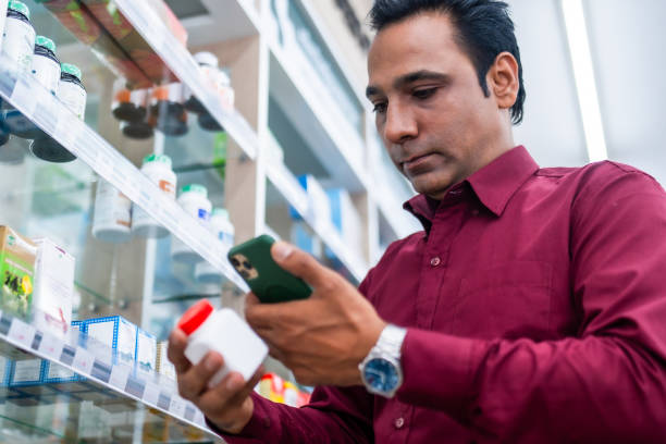 istock A customer in a pharmacy store examines a medicine bottle while using a smartphone, showcasing modern healthcare and retail services. 2164985583