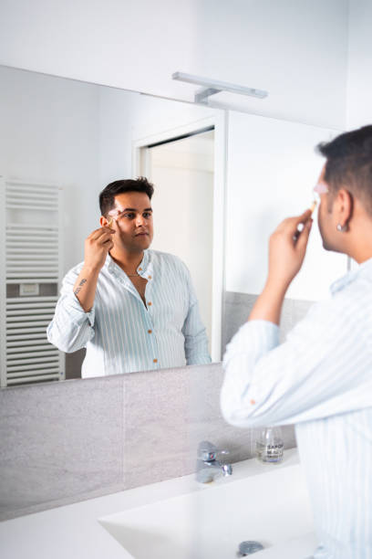 istock Man applying facial skincare routine in bathroom mirror 2164985896