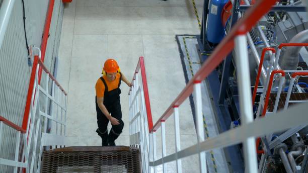 istock Industrial manager oversees night shift operations, climbs industrial stairs, ensuring compliance with safety standards. Wearing safety gear, monitors production processes and worker performance. 2164997585