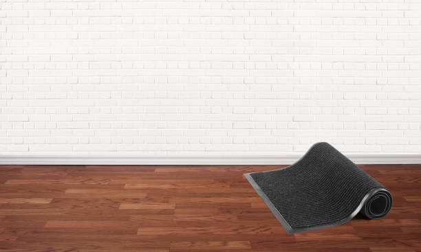 istock Rolled black protective door mat in a room with brick walls 2165015850
