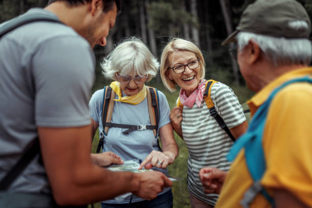 istock Mature and senior hikers checking map with their guide at forest 2165017660