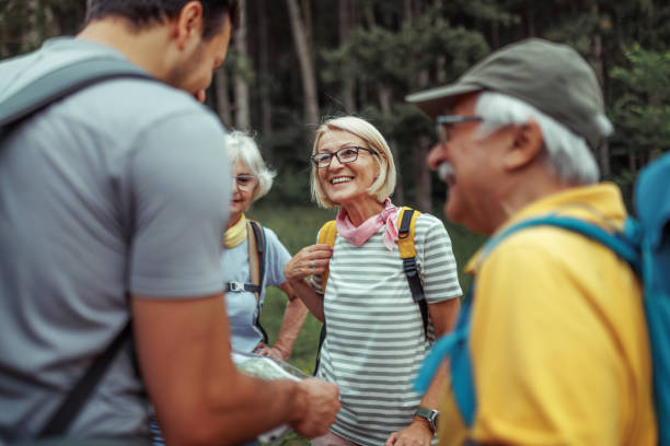 istock Mature and senior hikers checking map with their guide at forest 2165017661