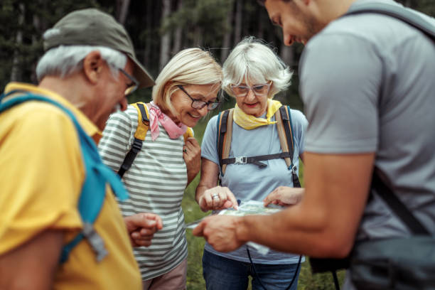 istock Mature and senior hikers checking map with their guide at forest 2165017664