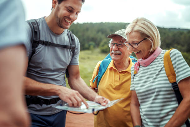 Senior hikers checking route on map with their young male guide at forest