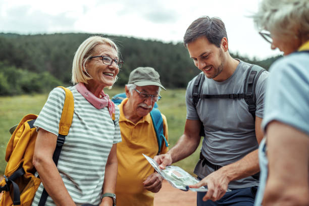 istock Senior hikers checking route on map with their young male guide at forest 2165017680