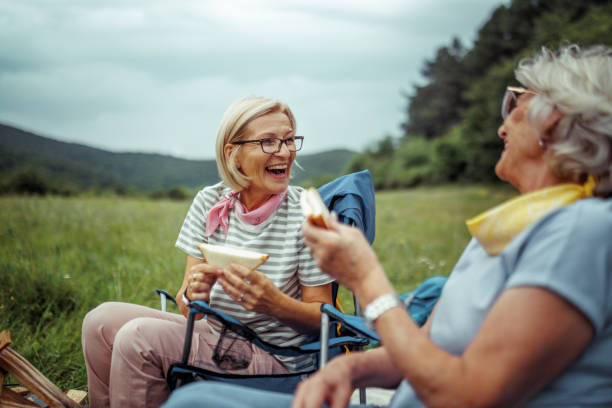 Mature female friends laughing while camping together at forest