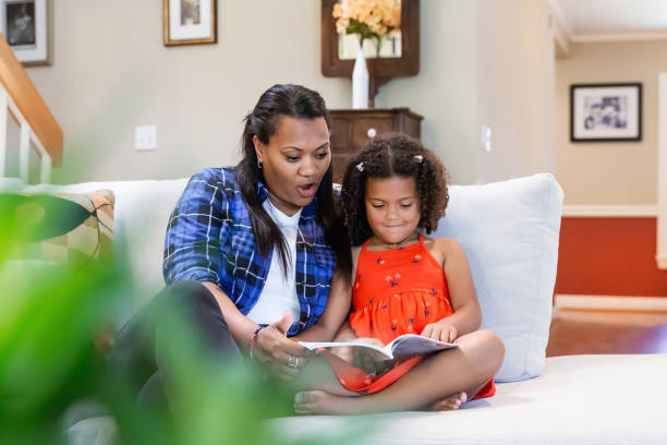 istock Mother and daughter reading a book on a couch 2165018327