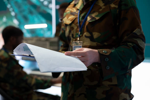 Trooper reading federal case file for a new defense operation, studying tactics and objectives before briefing the soldiers. Army specialist creating attack plans to ensure mission success.