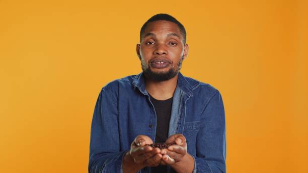 istock African american cheerful guy posing with black roasted coffee beans 2165024361